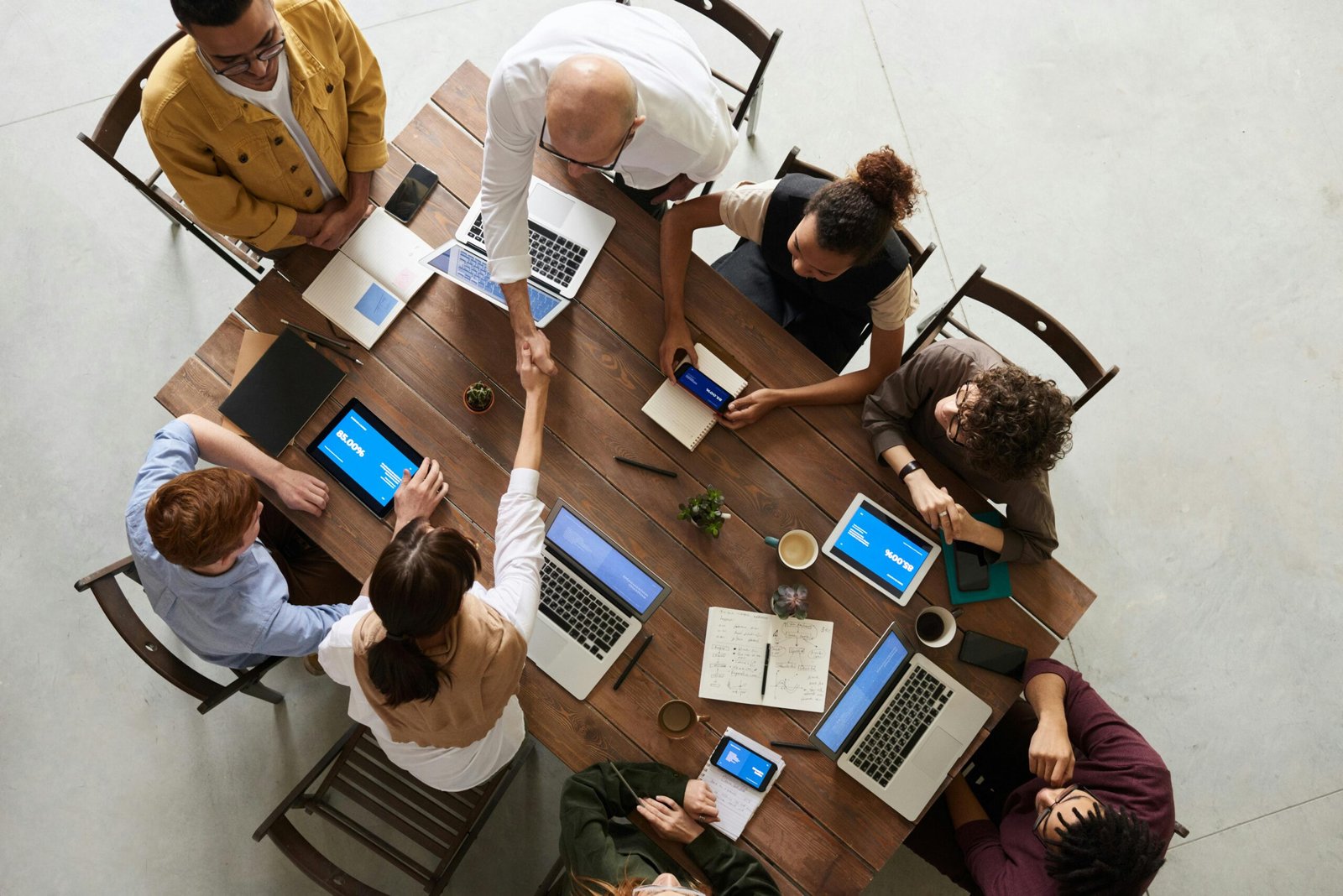 my home Top view of a diverse team collaborating in an office setting with laptops and tablets, promoting cooperation.