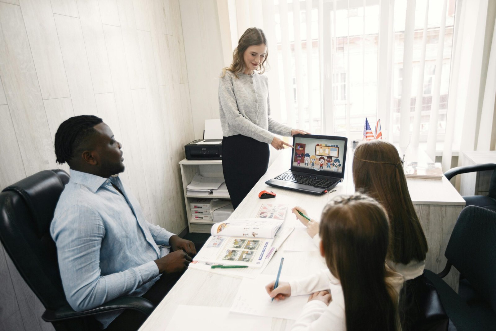 my home Colleagues engaging in a collaborative meeting around a laptop in a bright office space.